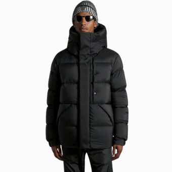 we zien een jonge man opstaan met een dik zwart heren donsjack aan