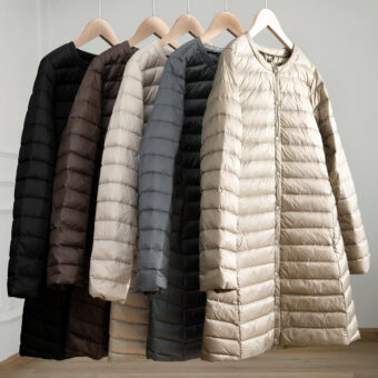 5 lichte en lange donsjassen in wit, grijs, zwart en bruin hingen op hangers.