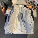 Omkeerbaar groot fleecejack voor dames, in de blauwe versie, op een houten meubelstuk met spulletjes er omheen.