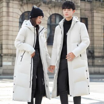 Lange uniseks zwarte of witte donsjas gedragen door een jonge man en een jonge vrouw in een besneeuwde straat