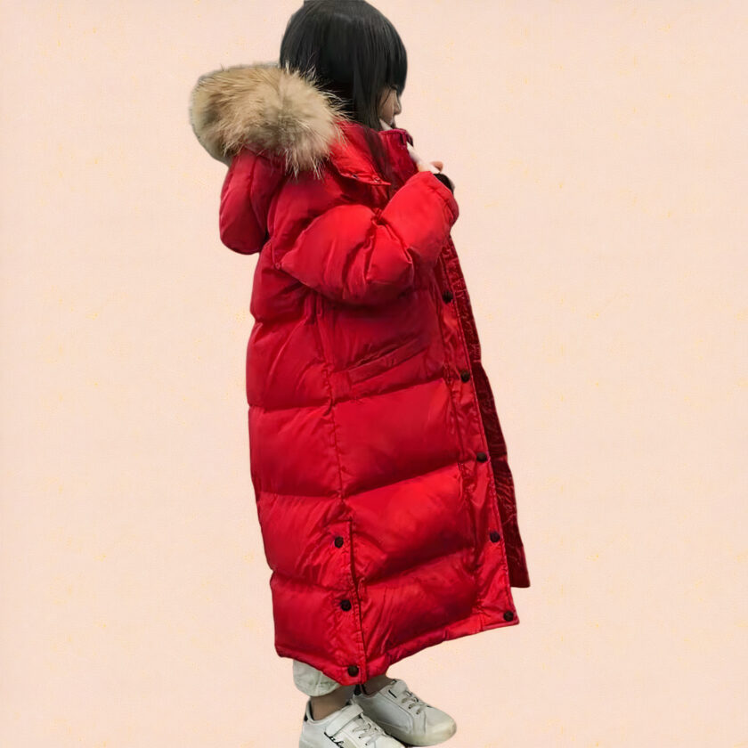 Klein meisje dat een rood kinderdonsjack met capuchon draagt op een roze achtergrond.