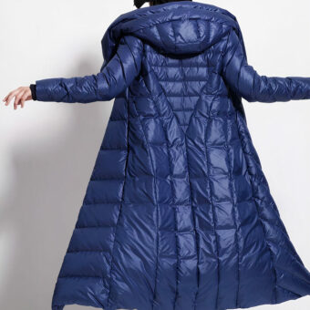 Lange marineblauwe waterdichte donsjas gedragen door een vrouw tegen een grijze achtergrond.