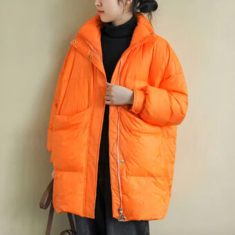 Vrouw draagt een oranje donsjack en houdt een handtas vast
