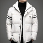 Op een grijze achtergrond wordt een wit gewatteerd donsjack, halfopen met zwarte drukknopen en twee zwarte strepen op de mouwen, gedragen door een man met daaronder een zwarte coltrui.