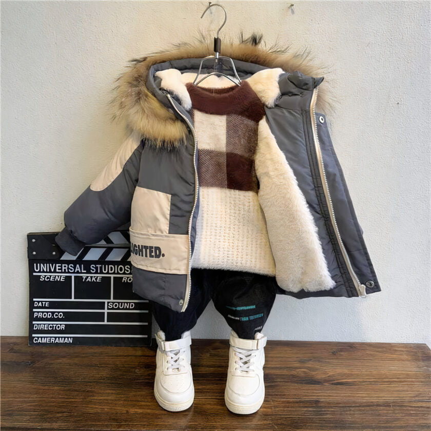 Een warme, dikke katoenen jas aan een kleerhanger tegen een grijze muur, parketvloer en witte schoenen op de vloer.