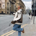 Vrouw draagt een bruin mouwloos donsjack van imitatiebont aan de buitenkant.