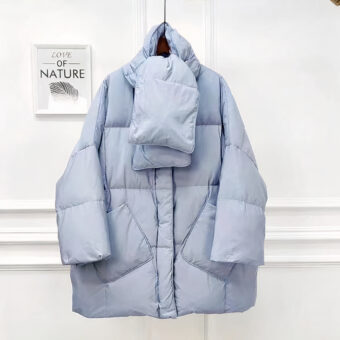 Het oversized lichtblauwe donsjack wordt gepresenteerd tegen een lichte, minimalistische achtergrond.