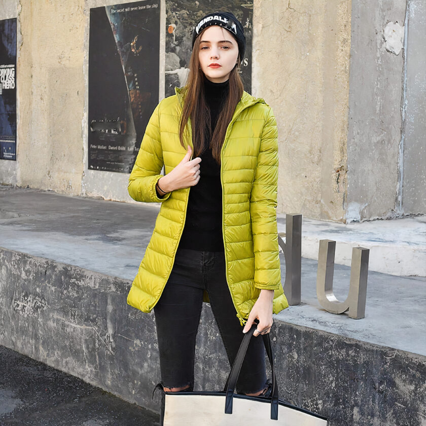 Vrouw op straat in een geel donsjack met een beige hoed en handtas