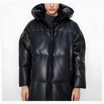 We zien een lange jonge man met een zeer bleke huid, waarschijnlijk een model, die een halflange kunstlederen donsjas draagt. Hij poseert tegen een witte achtergrond en glimlacht niet.