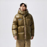 Foto van een man met een glanzende donsjas tegen een grijze achtergrond