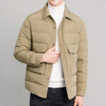 Foto van een man met een kort kaki donsjack tegen een grijze achtergrond