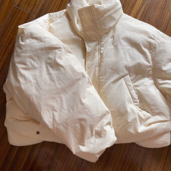 Foto van een kort beige donsjack op een parketvloer