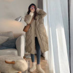 Foto van een vrouw met een lange kaki donsjas in een salon