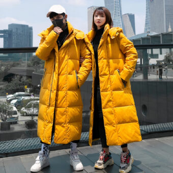 Twee mensen op een balkon, met lange gele jassen aan