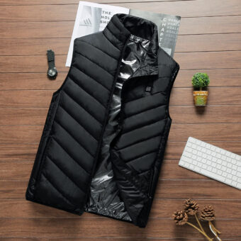 Mouwloos elektrisch verwarmd winterdonsjack in zwart, op een houten onderstel, met een plant ernaast en andere prullaria.