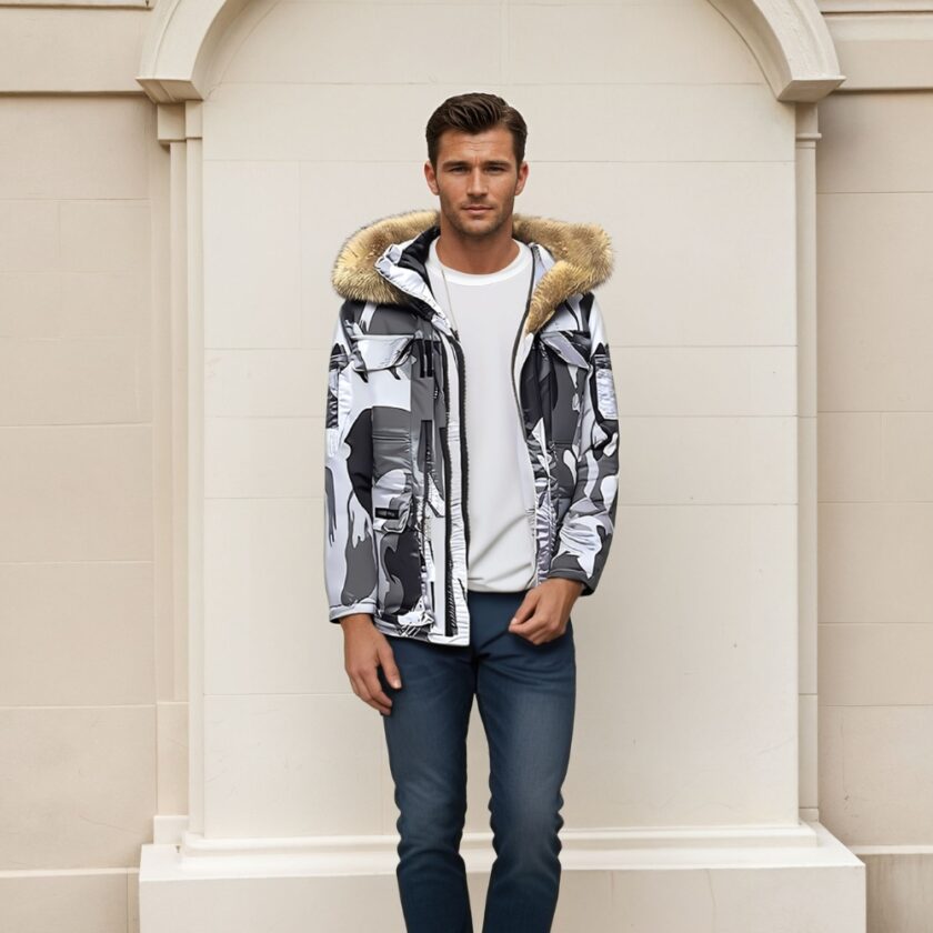Een man met bruin haar draagt een donkerblauwe spijkerbroek, een wit topje en een donsjack met witte, grijze en zwarte camouflagepatronen en een capuchon van bruin bont. Achter hem een beige stenen muur.
