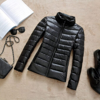 Dun kort zwart donsjack voor dames met hoge kraag, plat op de grond gelegd