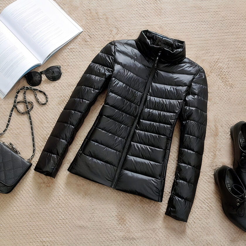 Dun kort zwart donsjack voor dames met hoge kraag, plat op de grond gelegd