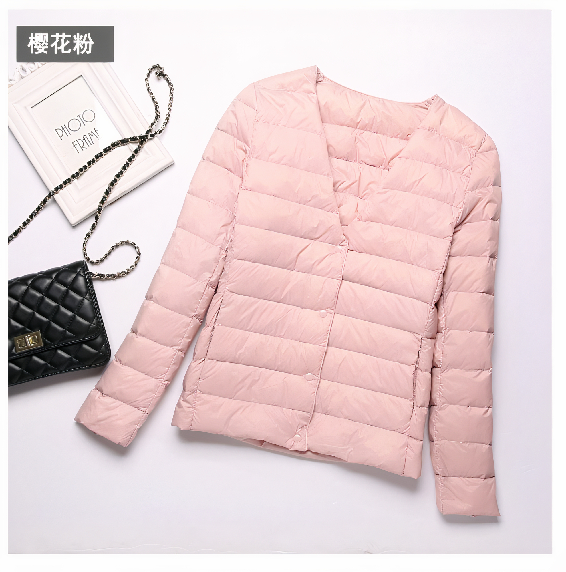 Dun, kort, roze jasje voor vrouwen, plat neergelegd op een witte achtergrond, met een handtas ernaast