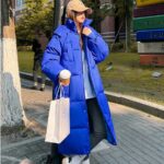 Foto van een vrouw in een lange blauwe donsjas op straat