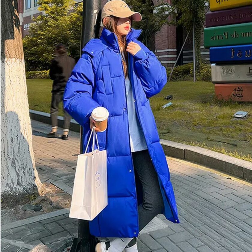 Foto van een vrouw in een lange blauwe donsjas op straat